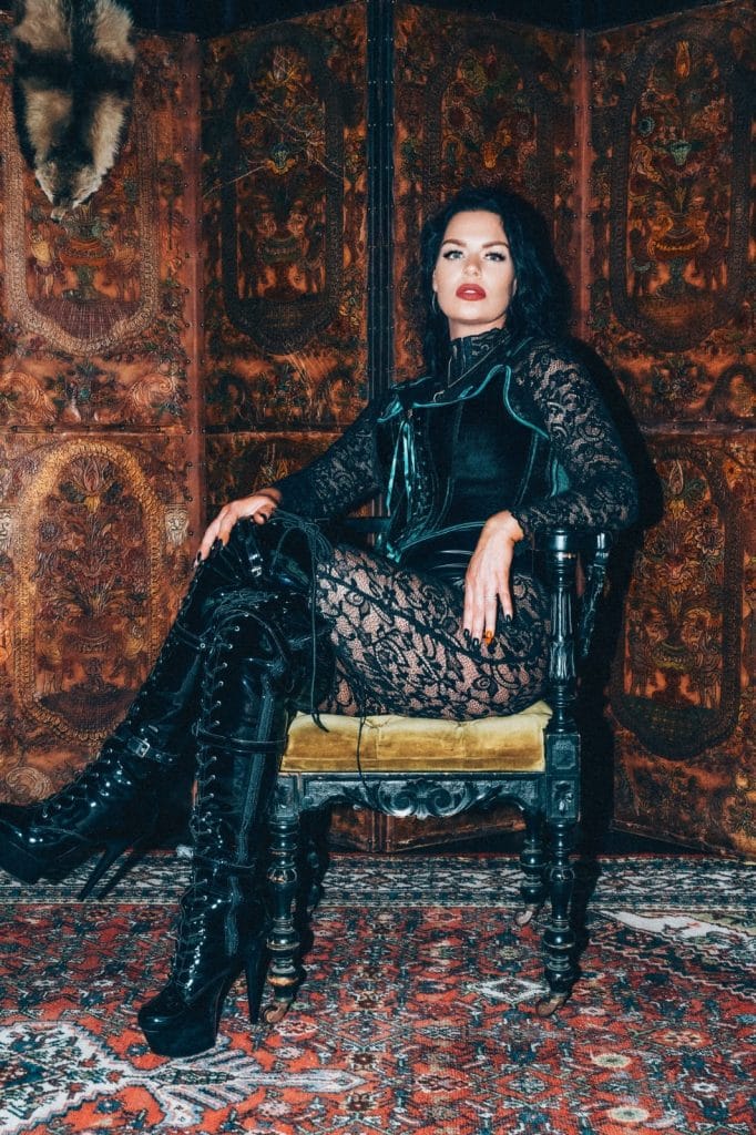 Mistress Charlotte seated on a throne-like chair in boots, face-sitting mistress