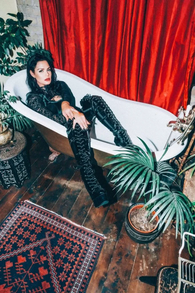 Mistress Charlotte O’Winter reclining in a clawfoot bath in black lace and thigh-high boots