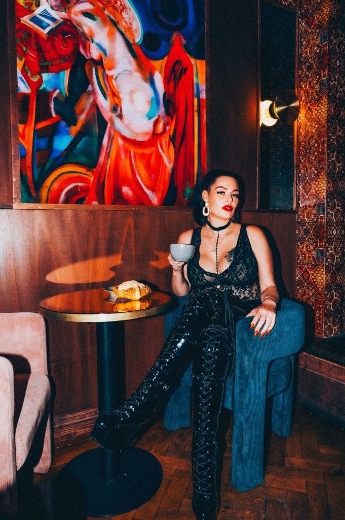 The Breakfast Club: coffee in a velvet booth, black lace and patent thigh-high boots beneath a vivid painting